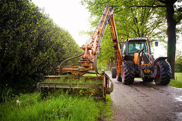 Trekker met maaier tijdens het maaien van een berm